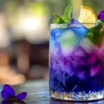 A vibrant purple Brazilian Mounjaro drink with ice, lemon, and mint, served outdoors in a beautiful setting.